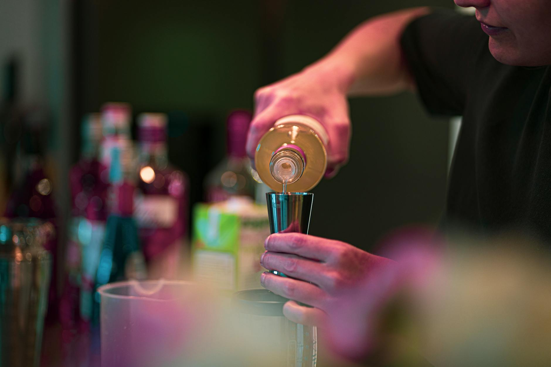 Glasses of wine, beer, and a cocktail with measuring jiggers and a small notebook for logging drinks on a kitchen counter