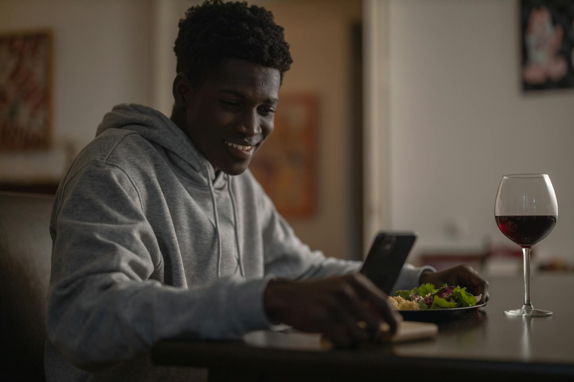 Person tracking a glass of red wine in a calorie tracking app at a casual dinner table with a healthy meal and water glass