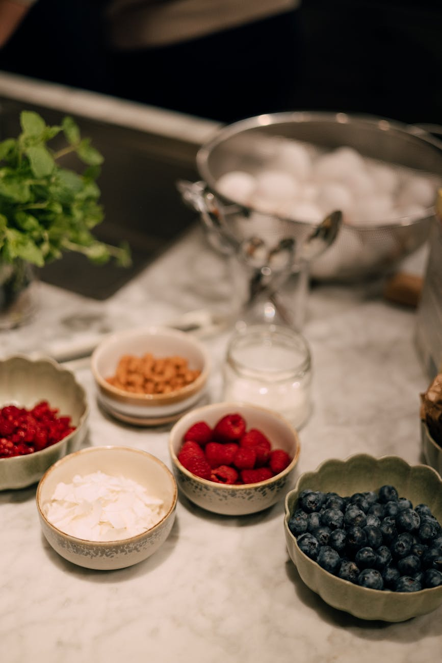 Colorful assortment of anti-inflammatory berries and dark fruits arranged in bowls alongside nuts and leafy greens