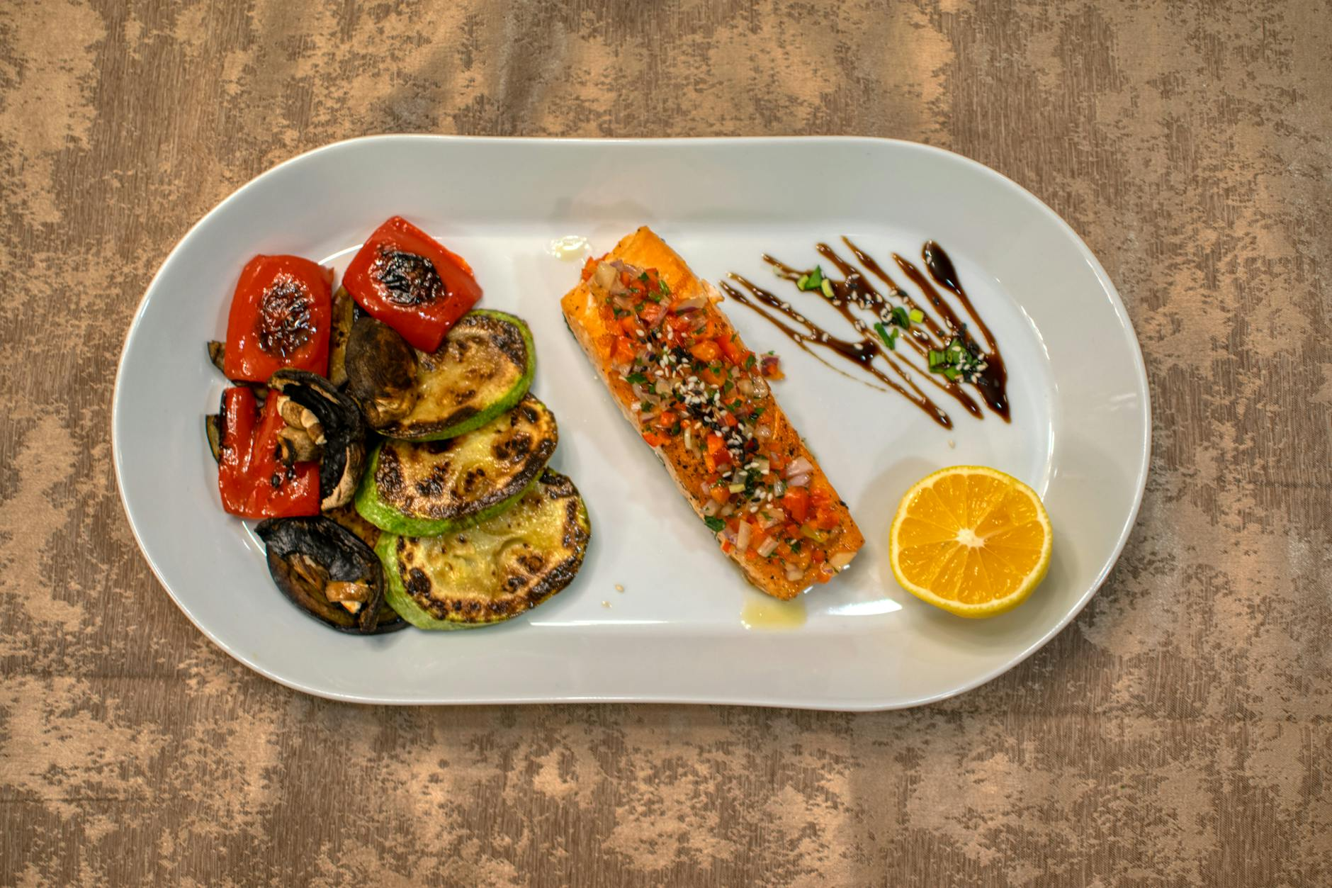 Colorful Mediterranean-style anti-inflammatory meal with grilled salmon, olive oil, vegetables, and herbs on a wooden table