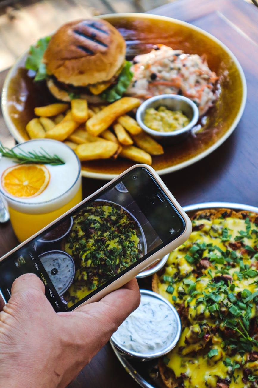 Person scanning a Nando's menu board with a smartphone tracking app open, and a half-chicken plate with salad on the bench beside it
