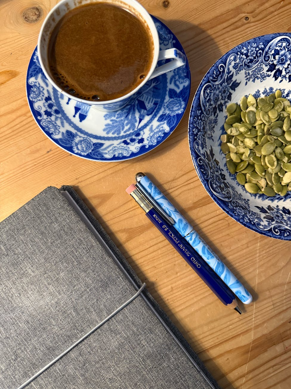 Person writing down calculations in a fitness journal next to a laptop showing a TDEE calculator and a healthy snack