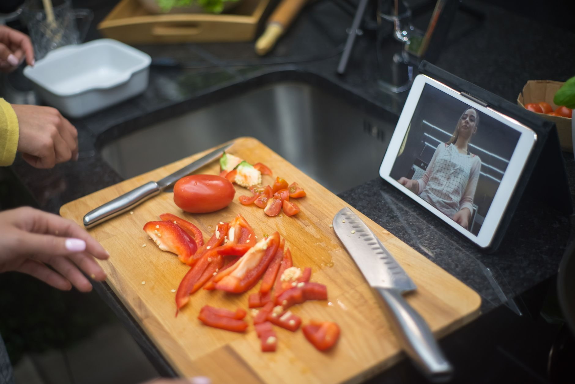 Sliced and steamed Australian vegetables — broccoli, zucchini, capsicum, sweet potato — on a digital kitchen scale beside a smartphone showing a calorie tracking app and a small notepad