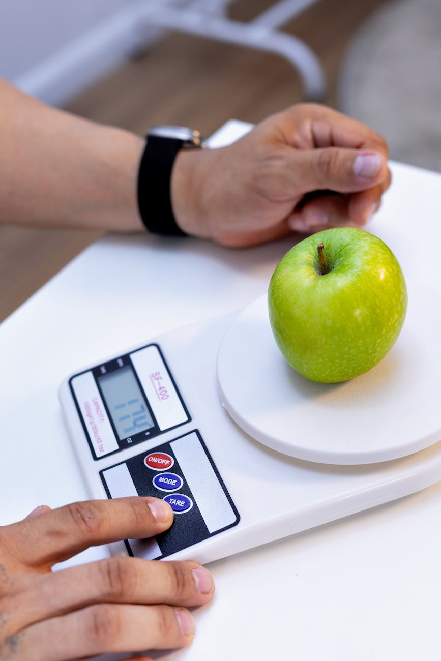 Balanced healthy meal portions on a plate with a food scale and measuring cups on a kitchen counter
