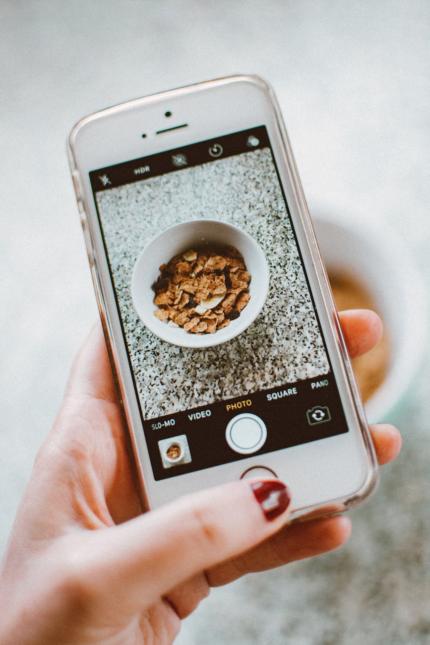 Person setting up a calorie tracking app on their smartphone next to a healthy breakfast at a sunlit kitchen counter