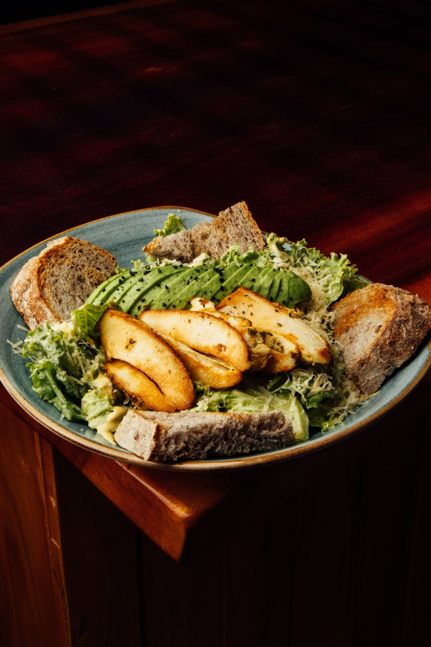Balanced high-protein meal with grilled chicken, quinoa, roasted vegetables, and avocado on a plate with a glass of water