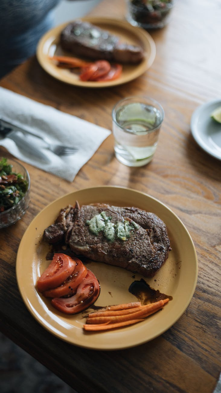 Cooked HelloFresh dinner plated on a sunlit Australian kitchen table beside a smartphone showing a calorie tracking app entry and a glass of water