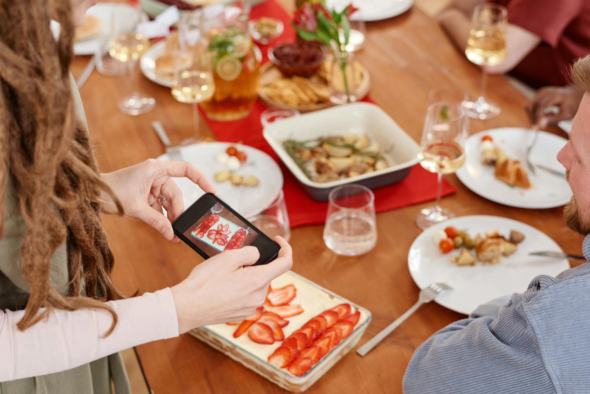 Person holding a smartphone at a natural angle to photograph a healthy meal with a fork and glass of water as reference objects