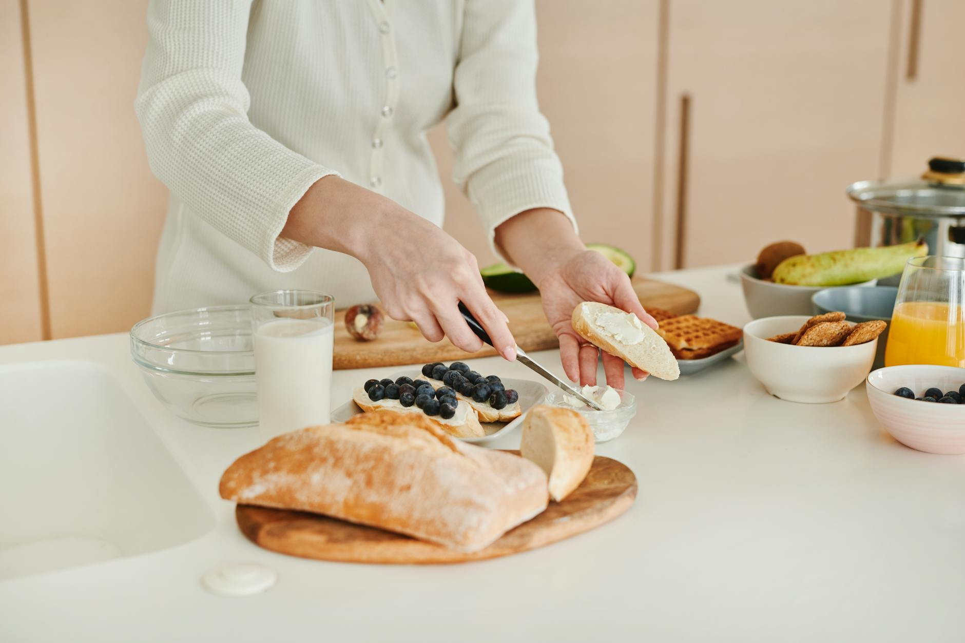 Person preparing a balanced meal in a bright kitchen with a clock on the wall showing an eating window timeframe