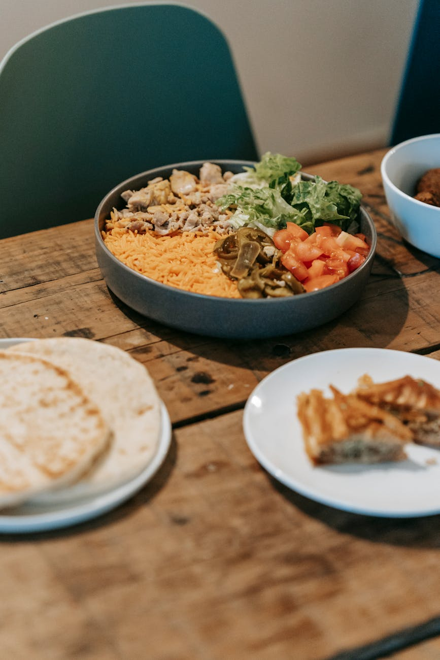 Smartphone displaying a daily calorie target alongside a balanced meal with grilled chicken, vegetables, and grains on a kitchen table