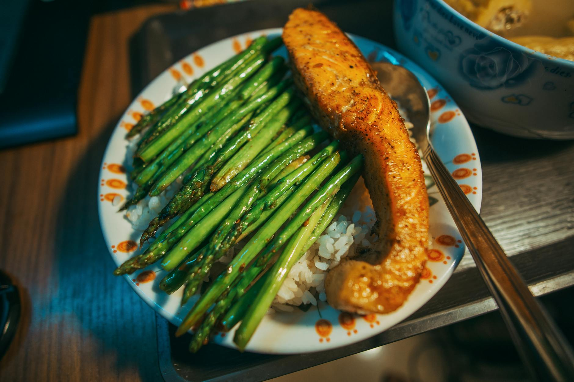 Person using a kitchen scale and smartphone app to quickly track a healthy dinner plate with salmon, vegetables, and rice