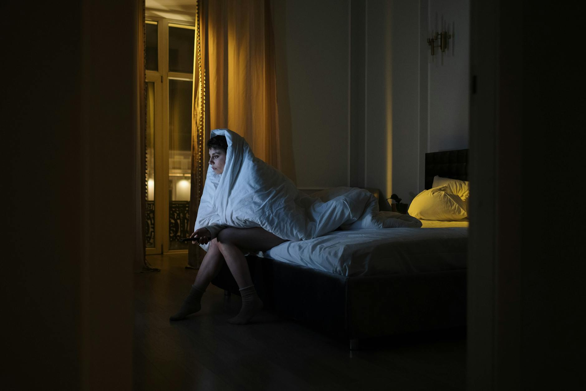 Person lying awake in bed at night with a clock showing late hours and a dimly lit room