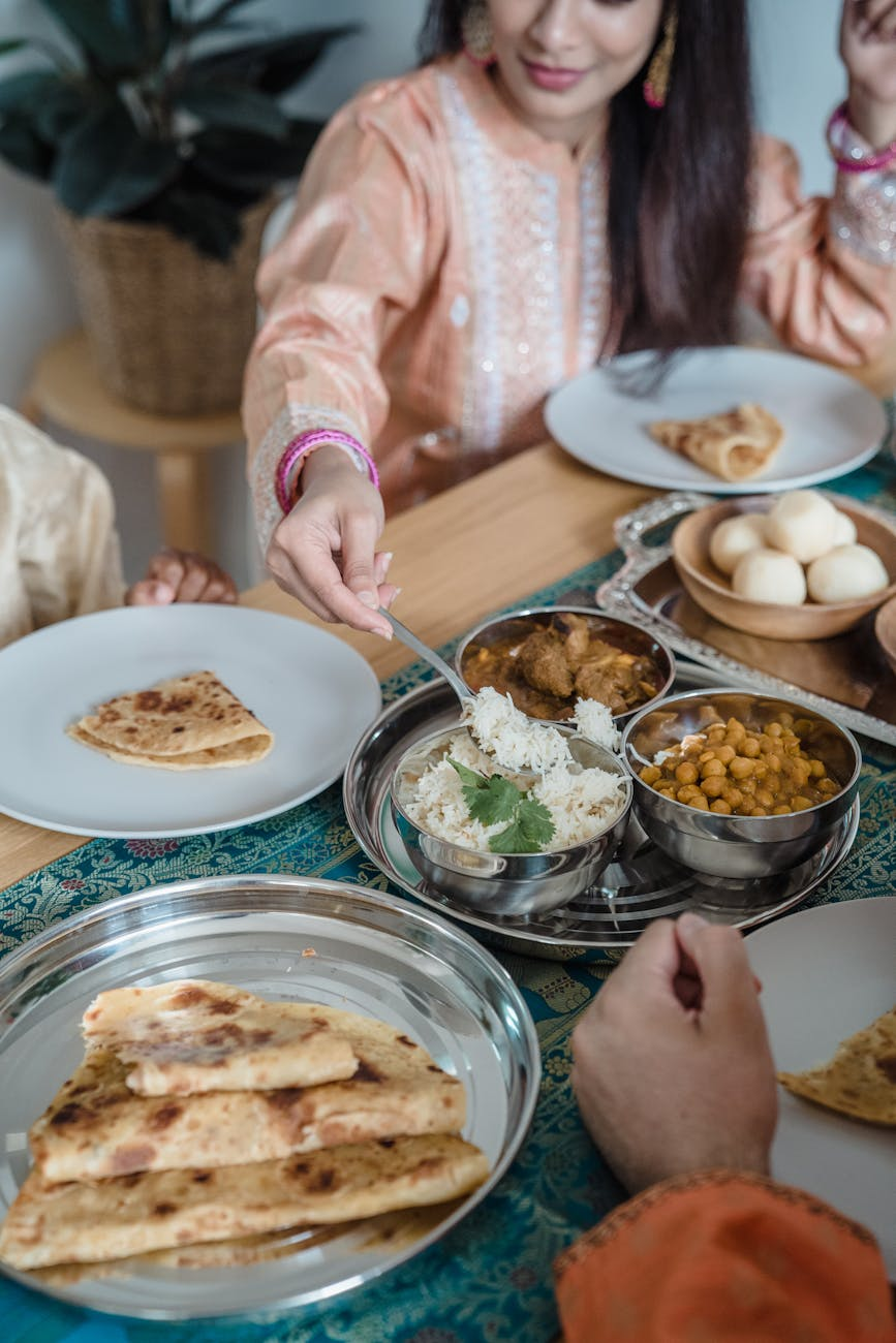Person using a smartphone to photograph a colorful Indian thali meal with rice, dal, vegetables, and naan on a traditional plate