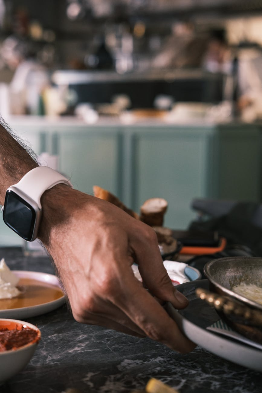 Person wearing a smartwatch while preparing a healthy post-workout meal with protein and vegetables in a kitchen